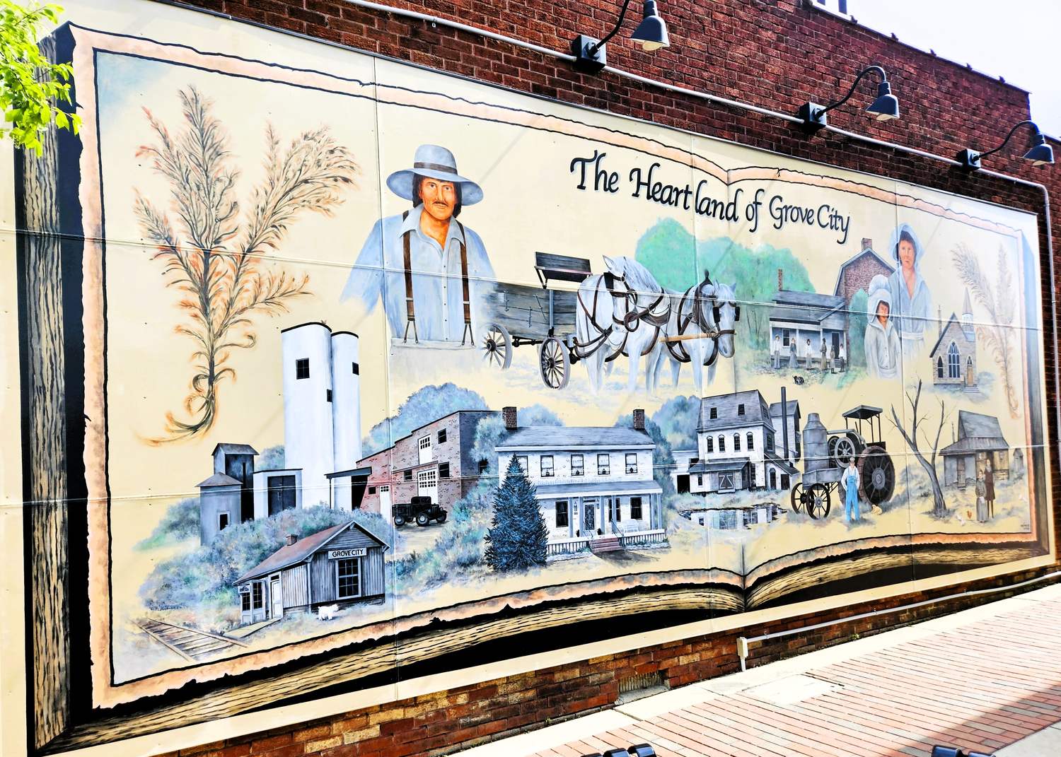 The Heartland of Grove City mural on Broadway, painted as an open book showing the railroad depot, farmhouses and early settlers