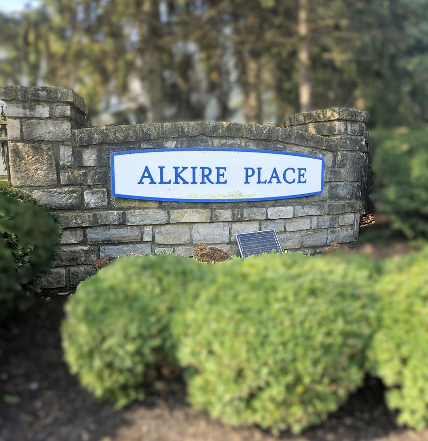 Alkire Place sign in blue and white on a stone wall