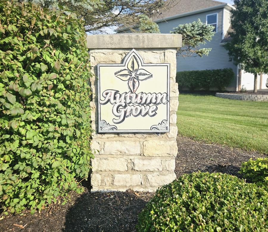Autumn Grove entrance sign on a stone pillar with a leaf motif
