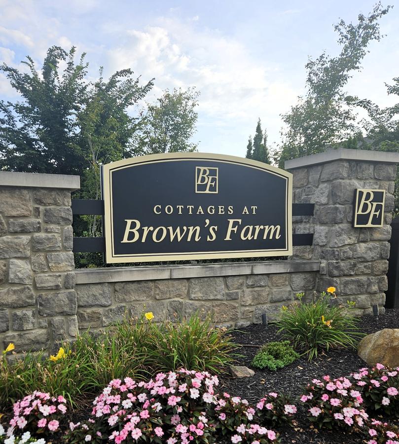 The Cottages at Brown's Farm entrance sign in black and gold on a stone wall