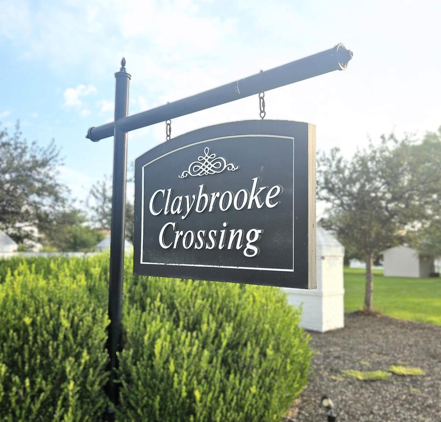 Claybrooke Crossing hanging sign above a clipped hedge