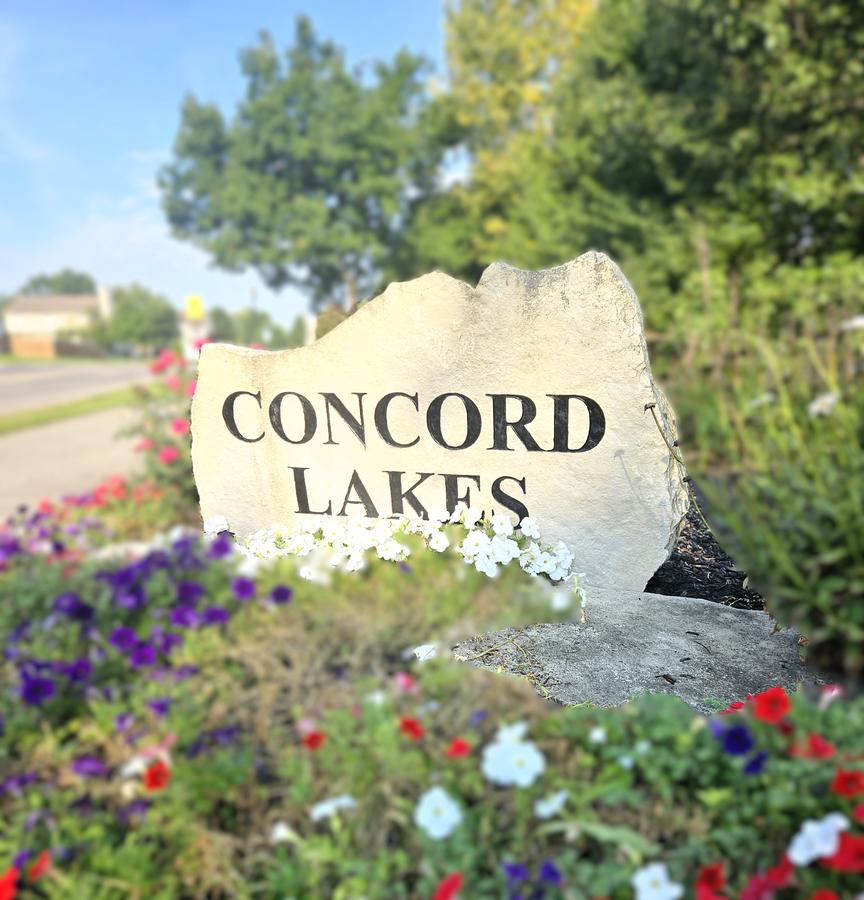 Concord Lakes carved stone sign surrounded by petunias