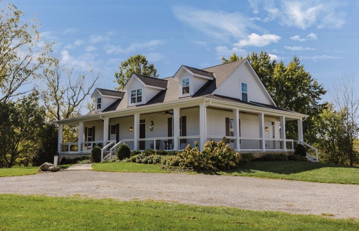 The farmhouse from the drive, with its wraparound front porch