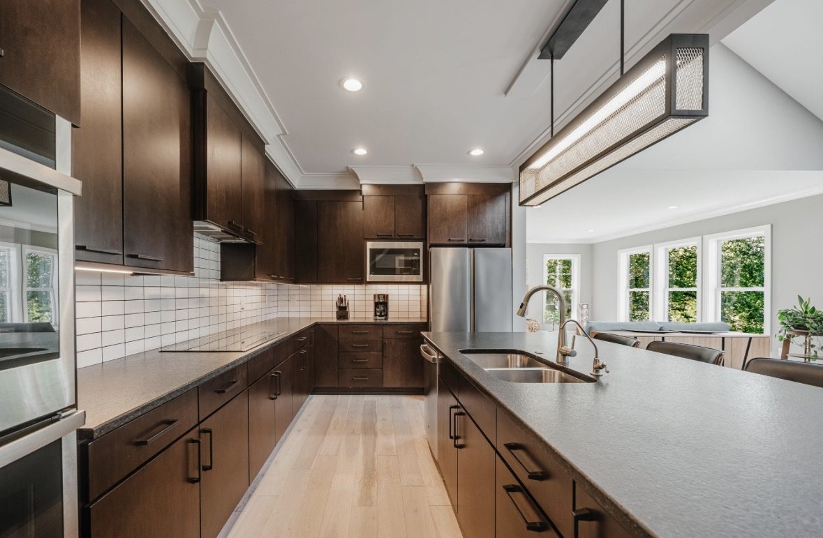 The kitchen, with dark wood cabinets and a long island looking into the living area