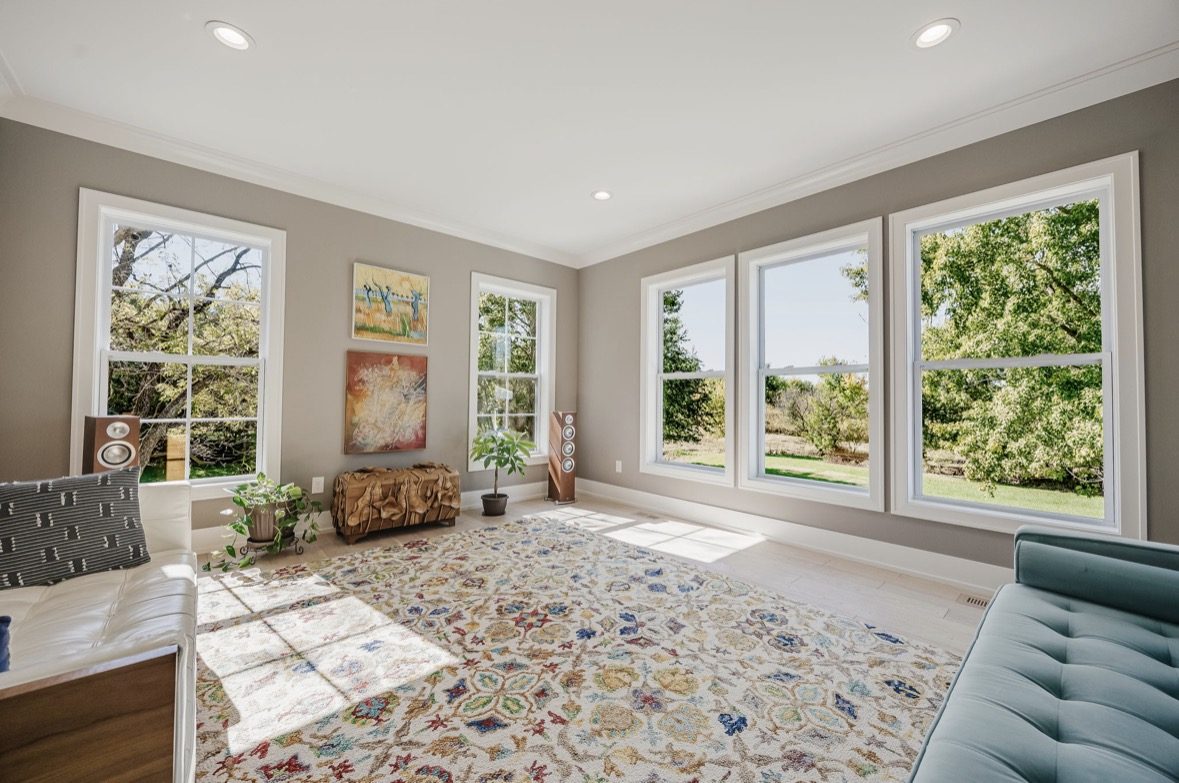 A bright living room with windows on two walls looking out over the yard